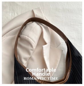 Close-up of black jacquard fabric and brown leather handle on a chic tote bag