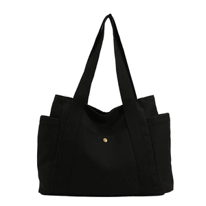 Black canvas tote bag with front pocket and gold button closure for stylish commuting