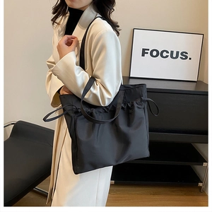 Detail of black large capacity tote bag with drawstring texture shown on shoulder