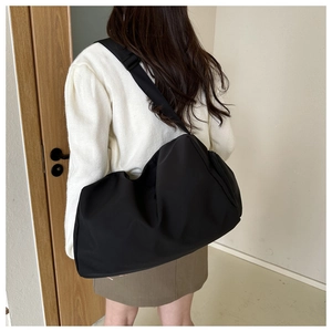 Detail of a large black slouchy tote bag showing the wide strap on a model's back