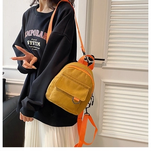 Détail d'un mini sac à dos en toile jaune avec des bretelles orange contrastantes