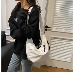 Side view of white canvas crossbody bag showing large capacity and adjustable strap