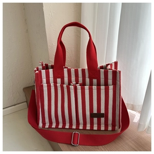 Detail of red and white striped canvas tote bag with front pocket and leather label