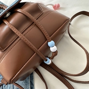 Vintage brown leather backpack with drawstring closure and heart charm decoration