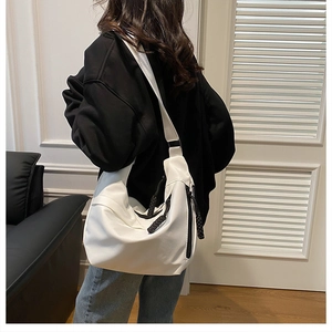 Detailed shot of white half-moon crossbody bag with black pull cord and adjustable strap