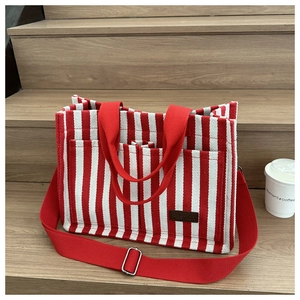 Detail of red and white striped canvas tote bag with front pockets and leather label