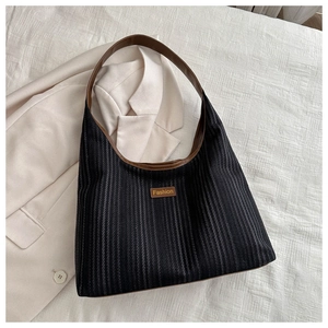 Detail of black striped canvas tote bag with brown leather handle and Fashion patch