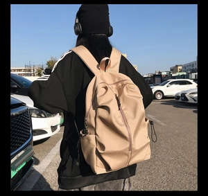 Detail of a beige waterproof nylon backpack with large zipper pocket and drawstring sides