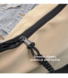 Detail of a smooth black metal zipper with a braided rope pull on a nylon tote bag