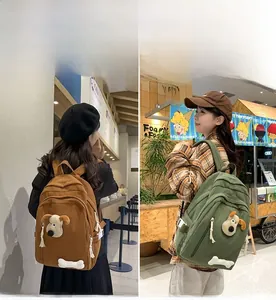 Detail of corduroy backpacks with Gromit character decor in brown and olive green colors