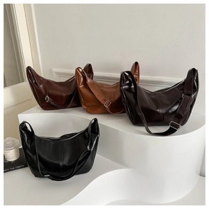 Multiple vintage half-moon crossbody bags displayed in earth tones on steps