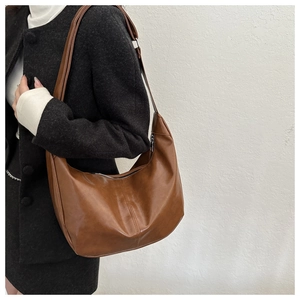 Close-up of brown PU leather shoulder bag featuring silver zipper and crescent shape