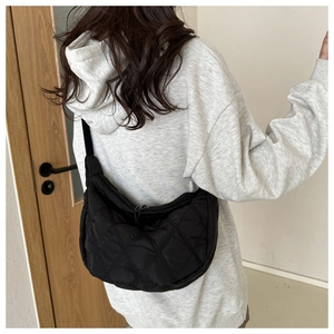 Model wearing a black quilted Oxford fabric crescent bag with diamond stitch detail
