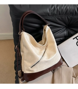 Close-up of beige and brown leather tote bag with gold zipper and textured surface