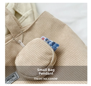 Detailed close-up of a beige corduroy mini pouch charm with a silver bead chain