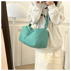 Detail of mint green nylon tote bag featuring adjustable strap and soft pleated texture