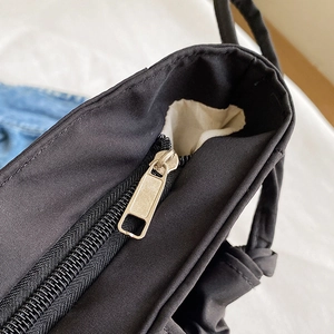 Large capacity black canvas tote bag showing top zipper closure detail and light inner lining