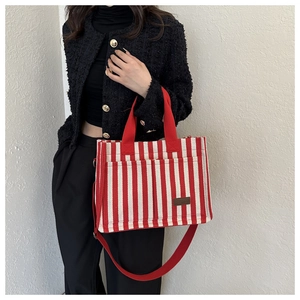 Detail of red and white striped canvas tote with leather label on fashion model