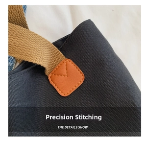 Detail of reinforced stitching on canvas bag with brown nylon strap and leather patch