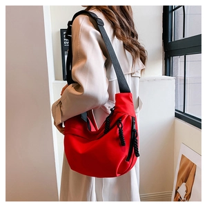 Side view of red crescent crossbody bag with adjustable strap worn by model