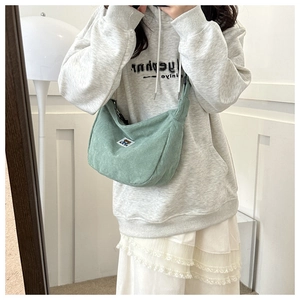 Detail of mint green corduroy dumpling bag featuring cute bear embroidery on shoulder strap