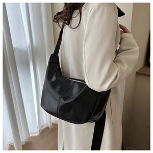 Sac croissant noir minimaliste porté à l'épaule dans un intérieur lumineux