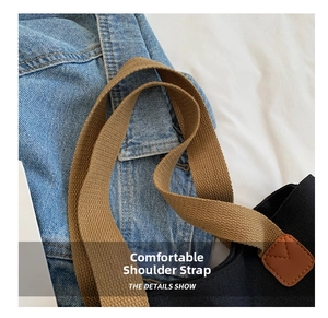Detail of durable brown woven shoulder strap with leather reinforcement on black canvas bag