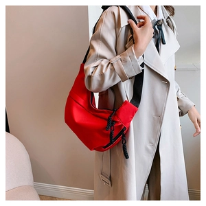 Detail of red nylon crescent crossbody bag with black strap and woven zipper pull