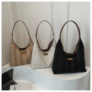 Three striped tote bags in khaki, beige, and black displayed with a fashion-branded plaque