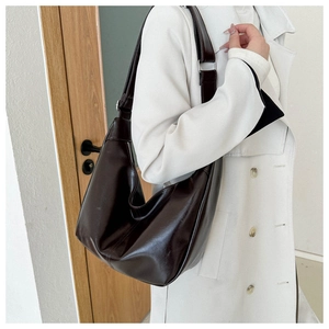 Détail du sac hobo en similicuir marron foncé avec bandoulière réglable sur un manteau