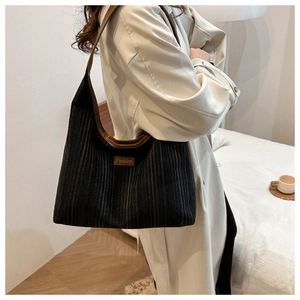 Close-up of black striped canvas tote bag with brown leather trim and fashion tag