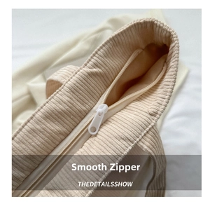 Detail view of the smooth white zipper and ribbed corduroy texture on the tote bag