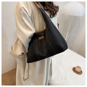 Close-up of black striped canvas tote bag with brown leather trim and fashion logo