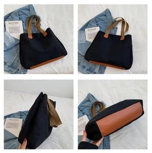 Detail view of a large black canvas tote with brown leather stitching and reinforced base