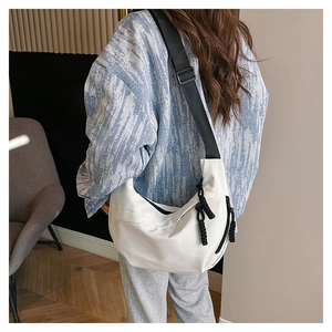 Back view of a white nylon crescent bag with adjustable black strap on a model