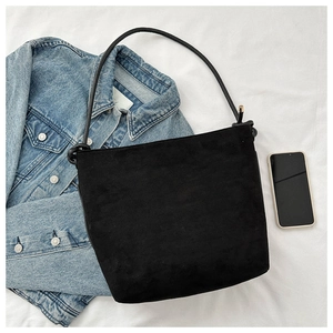 Detail of black matte suede bucket bag with stylish knotted strap on casual denim