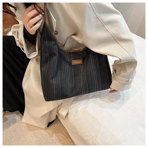 Detail of grey striped canvas tote bag with brown leather trim and fashion brand tag
