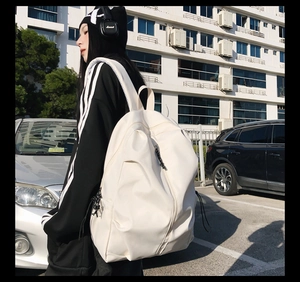 Minimalist white large-capacity backpack shown in a city street setting during daily use
