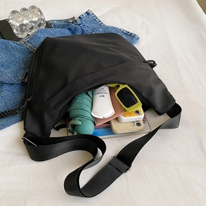 Black Oxford cloth crossbody bag with large capacity, shown with daily essentials