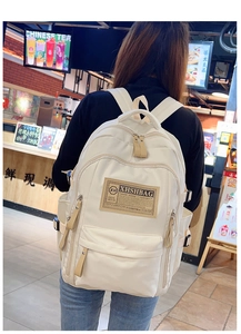 Dettaglio dello zaino in nylon bianco crema con etichetta del marchio in pelle marrone