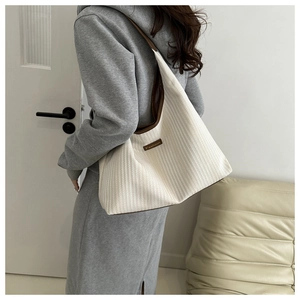Detail of cream knitted tote bag with brown trim and Fashion label on shoulder