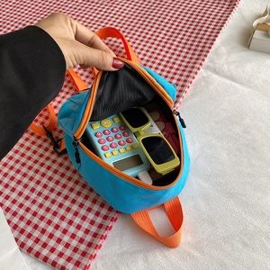 Mini sac à dos en toile bleue avec bretelles orange montrant le rangement intérieur