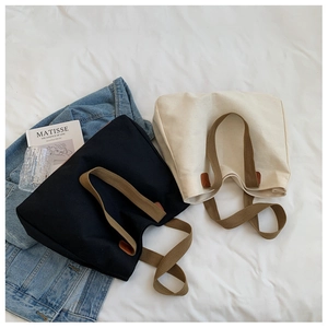 Detail of minimalist canvas tote bags in black and cream white with woven brown handles
