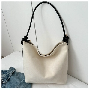 Detail of minimalist cream canvas tote bag featuring black knotted handles and magnetic closure