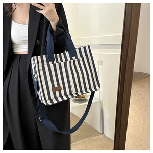 Detail of blue and white striped canvas tote with brown leather tag and strap
