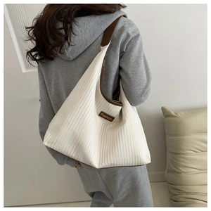Detailed back view of a person wearing a beige canvas hobo bag with brown leather accents
