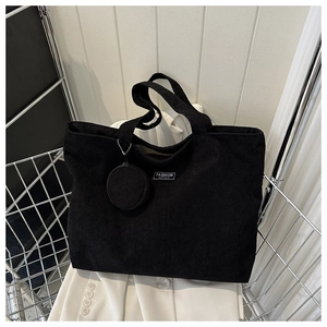Detail of black corduroy tote bag with Fashion Instinct label and small round pouch