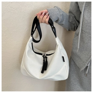 Detail view of white crescent bag with black adjustable strap and dual zipper closure