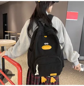 Detailed view of black corduroy cartoon duck backpack worn by a model in casual setting