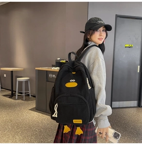 Detail of black corduroy cartoon duck backpack featuring 3D feet and front zipper pocket